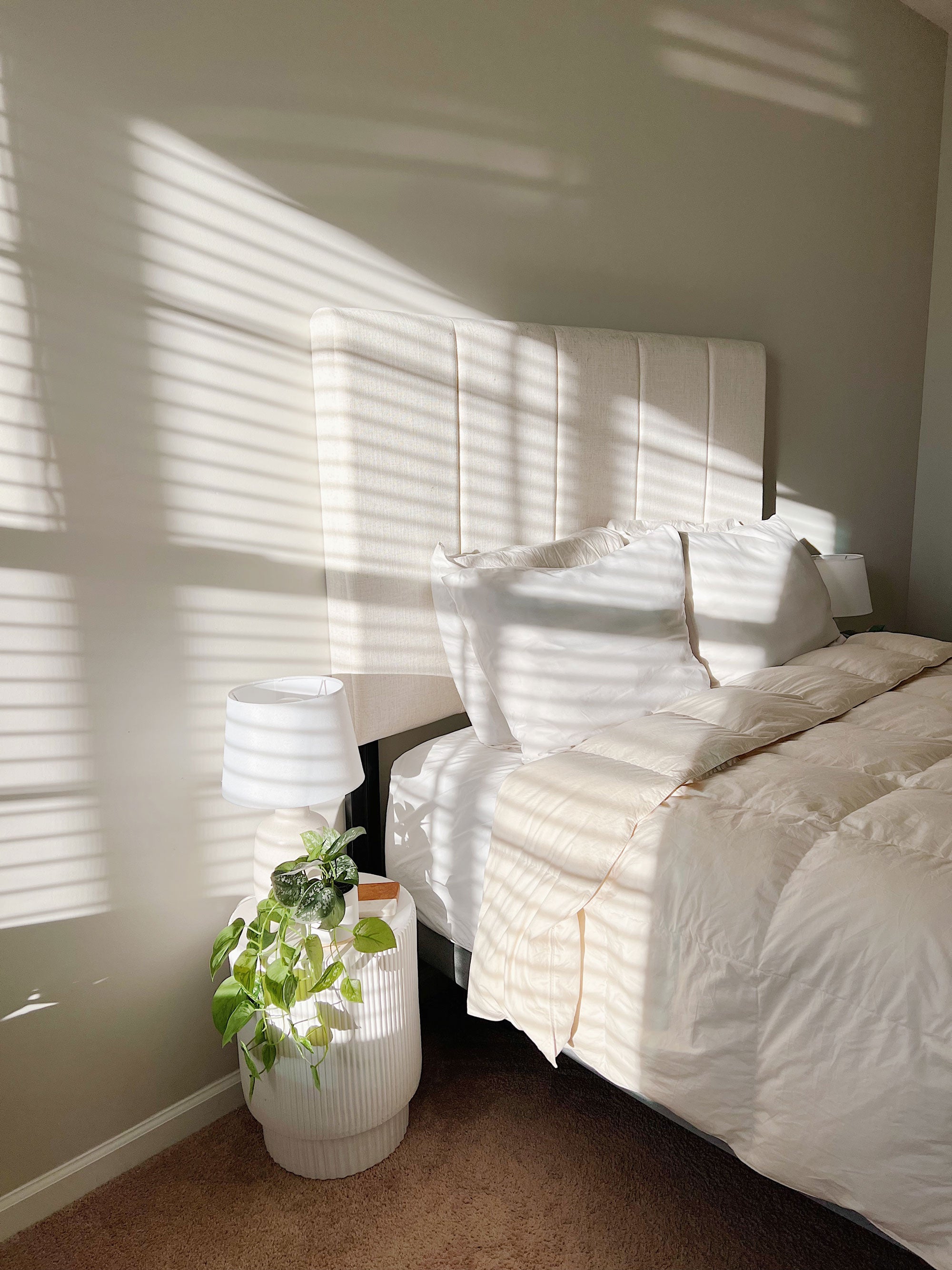 a bed with white bedding and a plant in a pot
