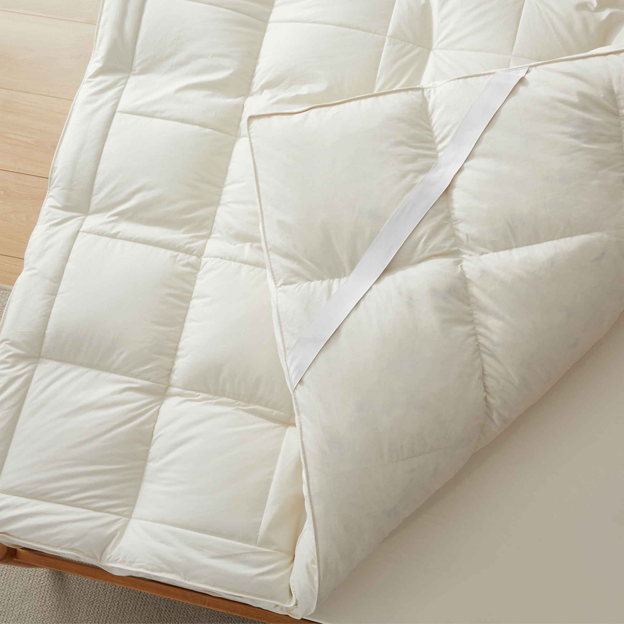 The plush surface of this feather blend mattress down topper is colored in pearly hues of off-white. Adding this feather mattress topper to your bedroom is an excellent choice for deep cushioning and additional comfort layer for a healthy sleep environment.
