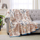 Cream-colored velvet throw blanket with intricate orange and navy medallion and vine patterns, finished with a navy blue border.