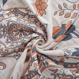 Cream-colored velvet throw blanket with intricate orange and navy medallion and vine patterns, finished with a navy blue border.
