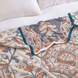 Cream-colored velvet throw blanket with intricate orange and navy medallion and vine patterns, finished with a navy blue border.