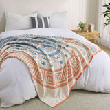 Cream-colored velvet throw blanket with intricate orange and navy medallion and vine patterns, finished with a navy blue border.