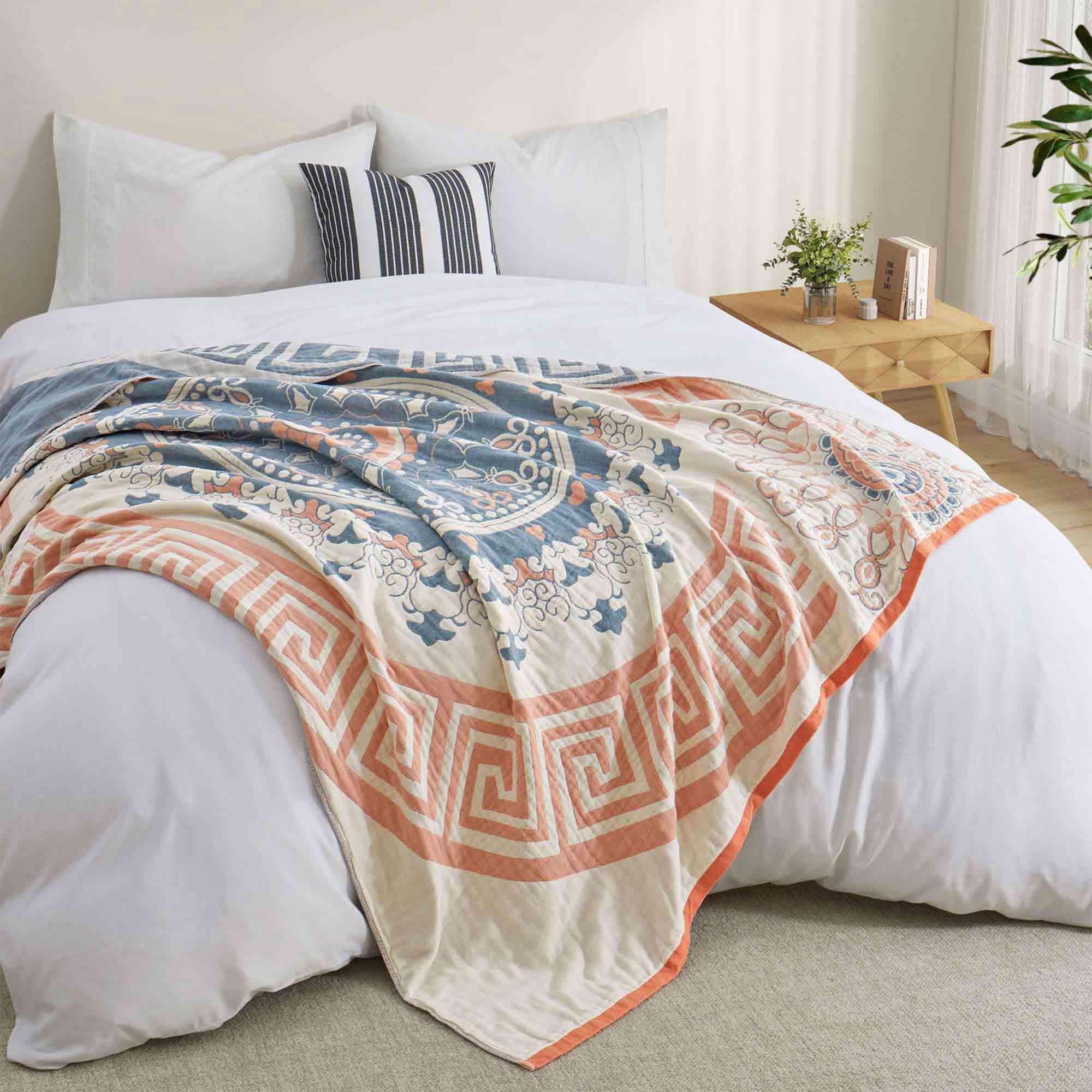 Cream-colored velvet throw blanket with intricate orange and navy medallion and vine patterns, finished with a navy blue border.