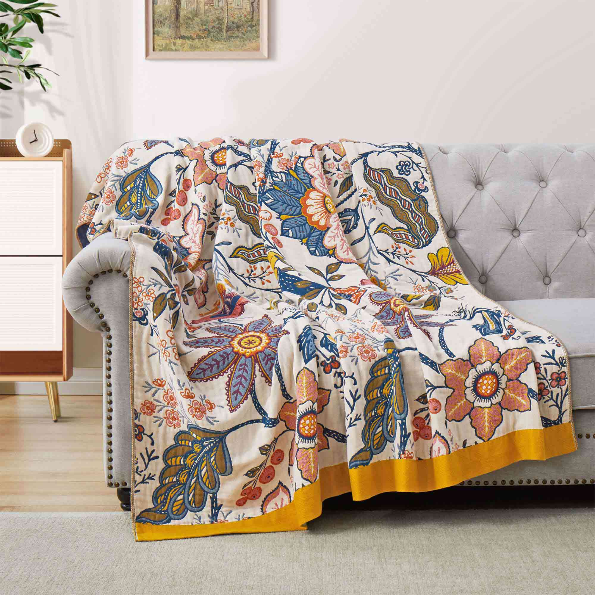 Cream-colored floral velvet throw blanket featuring vibrant red, blue, and yellow botanical patterns with a golden yellow border.