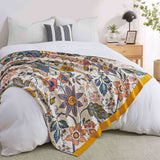 Cream-colored floral velvet throw blanket featuring vibrant red, blue, and yellow botanical patterns with a golden yellow border.