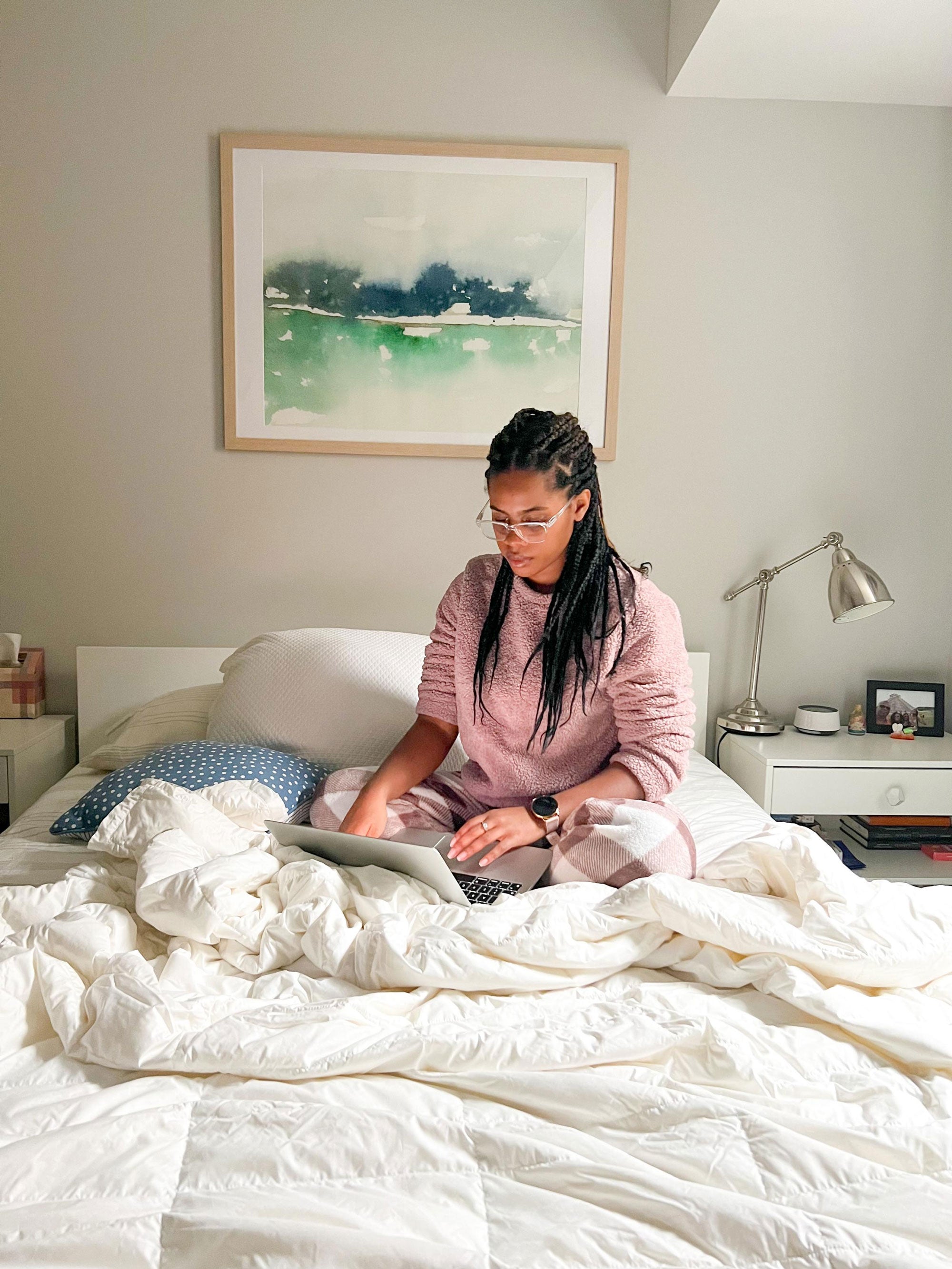 a person sitting on a bed with a laptop