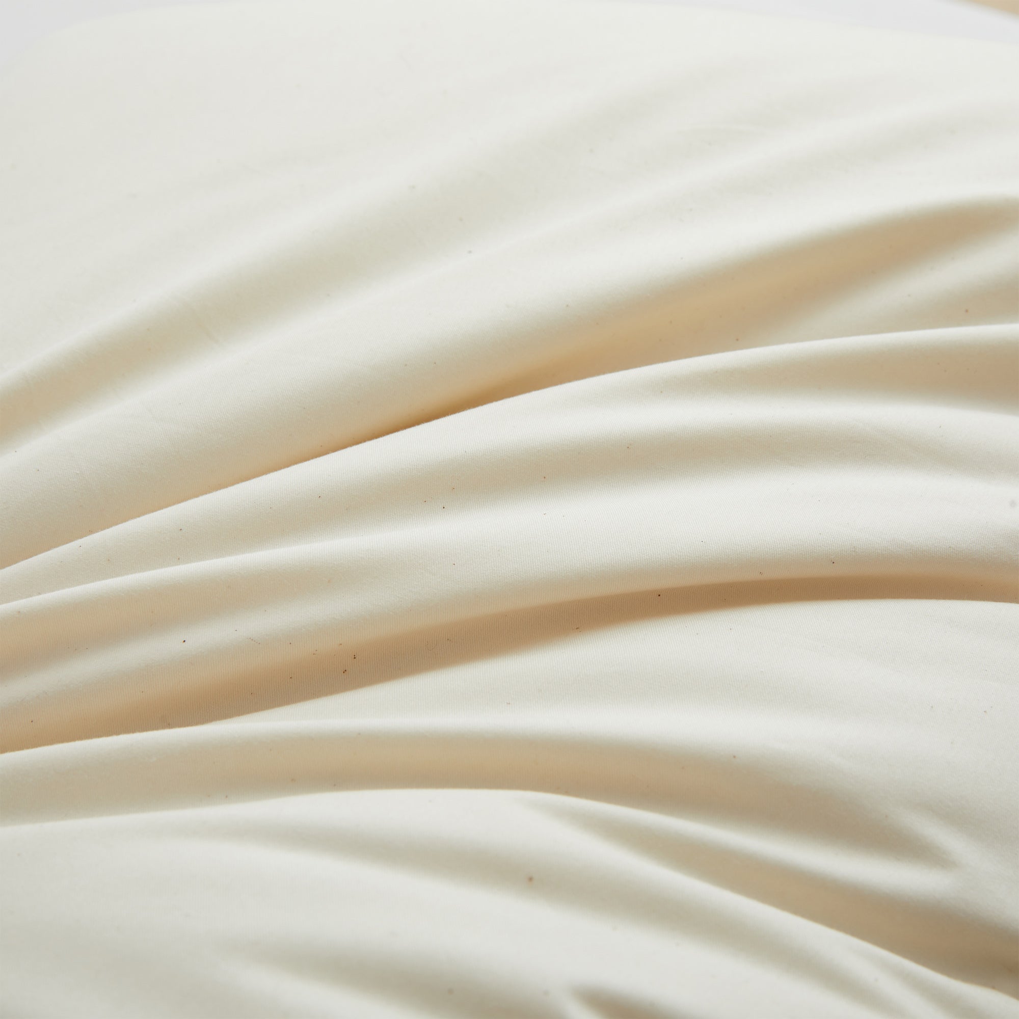 Close-up of Set of 2 Organic Cotton 90% Down Feather Bed Pillows made in Germany, showing cream-colored fabric with gentle folds and soft shadows.