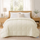 A neatly made bed featuring the Cotton Oversized Down Blanket in cream, paired with premium white down pillows and wooden furniture in a sunlit bedroom.