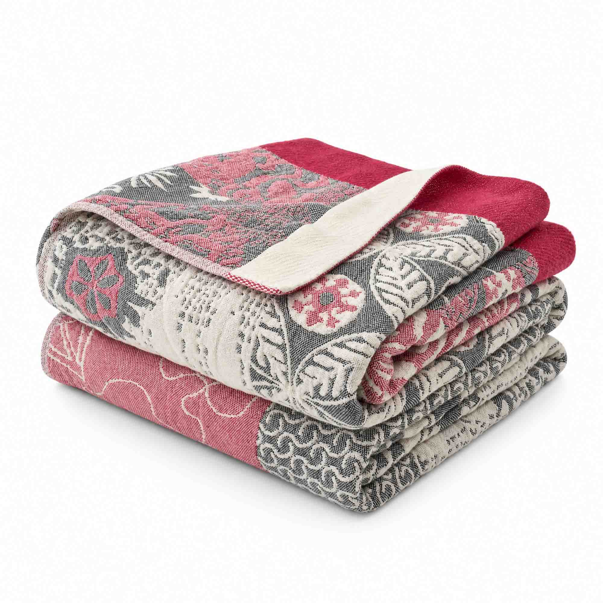 Two folded Boho Cotton Throw Blankets, featuring red, gray, and cream floral and leaf patterns, are stacked on a white background in a stylish multi-color design reminiscent of cotton jacquard.
