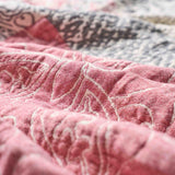 Close-up of the Boho Cotton Throw Blanket, showcasing its pink and white jacquard patterns with visible textured stitching that highlights the intricate craftsmanship.
