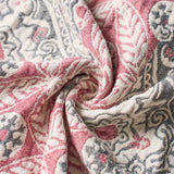 Close-up of textured fabric with red and gray intricate patterns, loosely gathered in the center—the Boho Cotton Throw Blanket featuring a rich, multi-color jacquard design.
