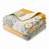 The Boho Cotton Throw Blanket, shown folded, displays a striking multi-color design in blue, white, and yellow with floral and geometric patterns on a white background. Crafted from cotton jacquard, this blanket brings vibrant boho style to any space.