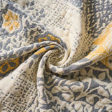Close-up of the Boho Cotton Throw Blanket, crafted from textured jacquard cotton fabric with gray, yellow, and cream floral patterns, softly twisted at the center for a cozy and stylish boho accent.