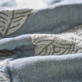 Close-up of the Boho Cotton Throw Blanket in light blue and white, featuring a subtle leaf pattern in jacquard weave and a soft, cozy texture.