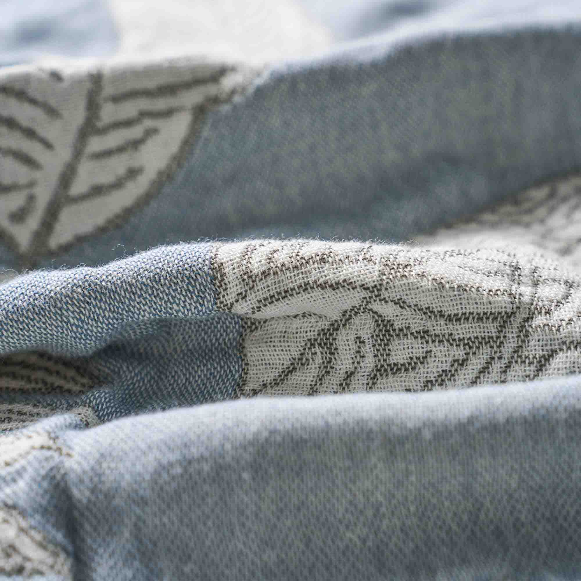 Close-up of the Boho Cotton Throw Blanket in light blue and white, featuring a subtle leaf pattern in jacquard weave and a soft, cozy texture.
