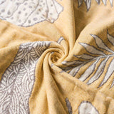 Beige and white patterned fabric twisted into a spiral, showing detailed texture and fine line designs—this Boho Cotton Throw Blanket adds a touch of elegance to any space.
