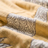 Close-up of yellow fabric with gray and white intricate patterns and visible woven texture, highlighting the beauty of the Boho Cotton Throw Blanket.