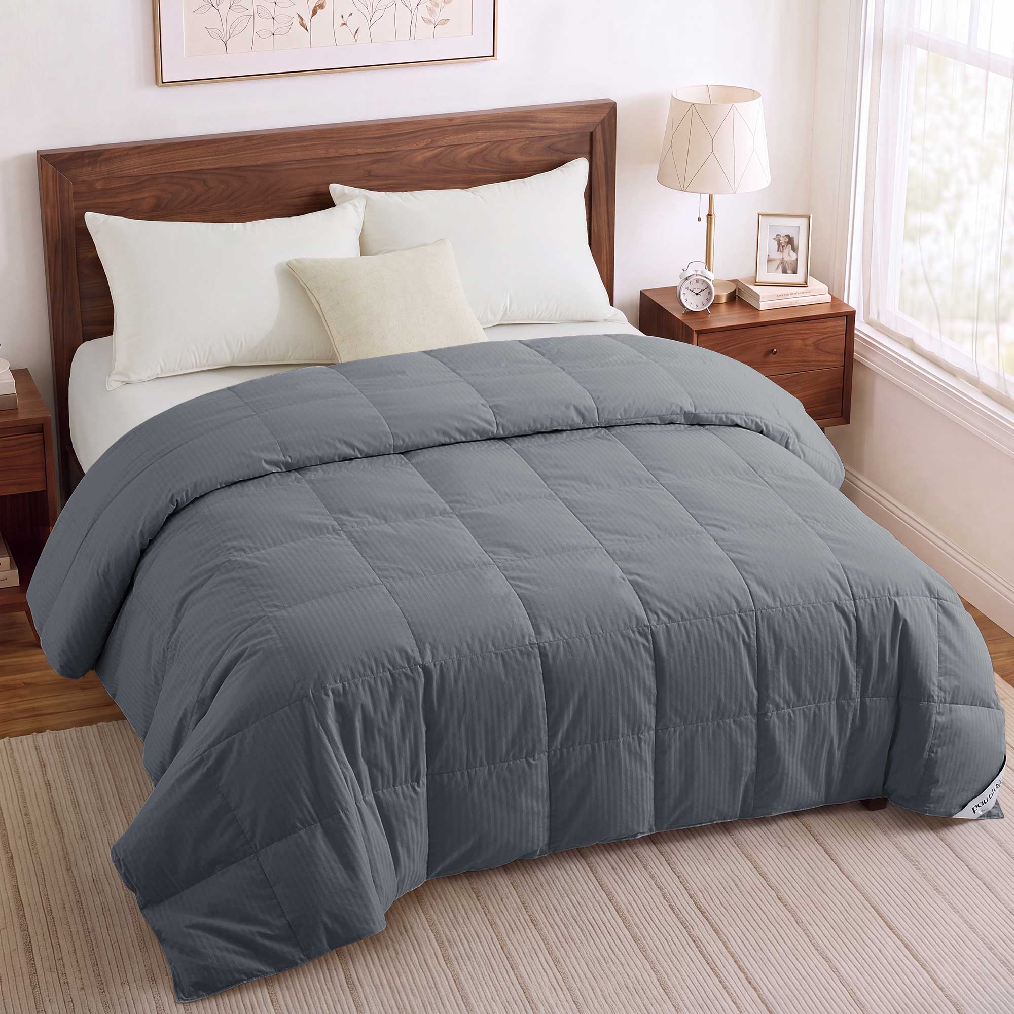 A neatly made bed featuring the Woven Stripe Down Blanket in gray, paired with white pillows and set against a wooden headboard in a cozy bedroom.