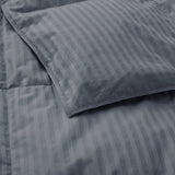 Close-up of a Woven Stripe Down Blanket in gray atop a neatly made bed, paired with a matching striped pillow.