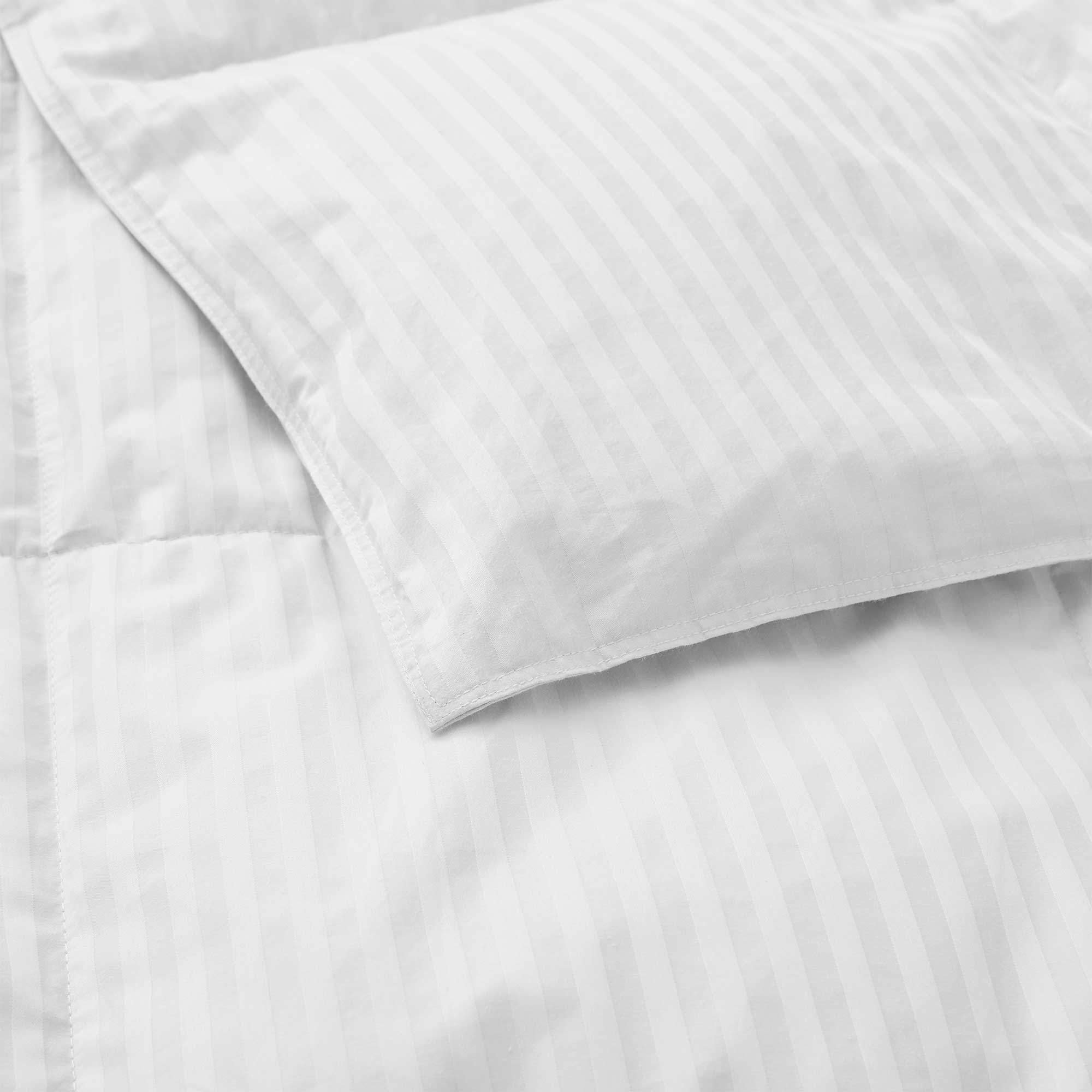 A close-up view of the Woven Stripe Down Blanket in white, featuring subtle vertical stripes.