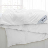 Woven Stripe Down Blanket draped over a bed with the label visible in the corner.