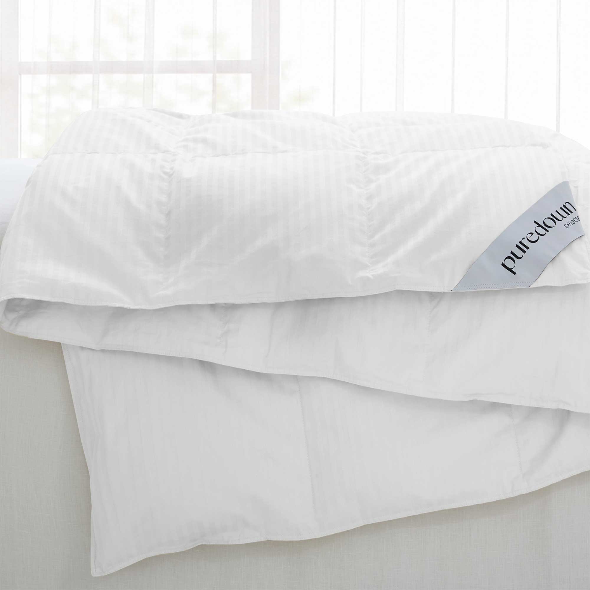 Woven Stripe Down Blanket draped over a bed with the label visible in the corner.