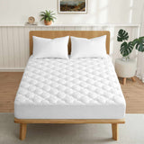 White mattress pad on a wooden bed in a bedroom setting with plants and decor.