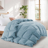 A neatly made bed in a bright bedroom, featuring the Premium Goose Feather Comforter in light blue, sits near a window with a potted plant.