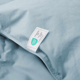 A close-up of the Premium Goose Feather Comforter in blue fabric, featuring an attached Oeko-Tex Standard 100 label.