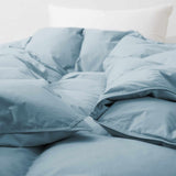 Premium Goose Feather Comforter in light blue on a bed with a white pillow in the background.