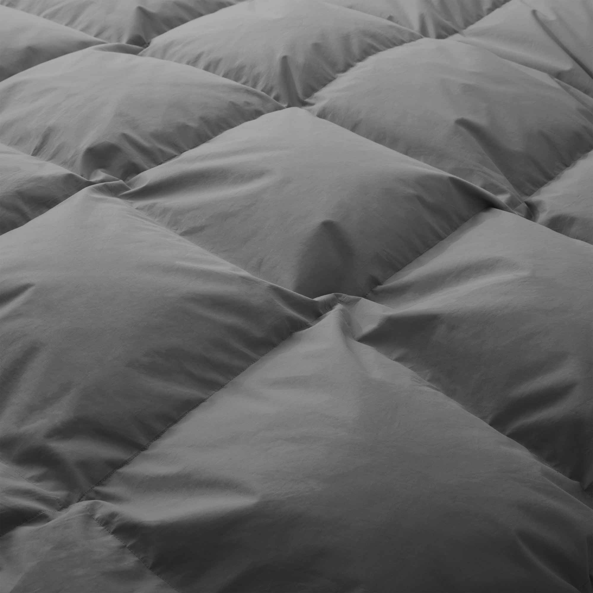 Close-up of the Premium Goose Feather Comforter in grey, highlighting its soft, puffy quilted squares arranged in a diamond pattern.