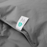 A Premium Goose Feather Comforter in gray fabric featuring a visible OEKO-TEX STANDARD 100 certification label on its surface.