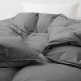 Close-up of the Premium Goose Feather Comforter in gray on a bed, with a white pillow in the background.