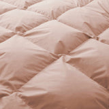 Close-up of the Premium Goose Feather Comforter, featuring a soft, peach color and a puffy, quilted square pattern.
