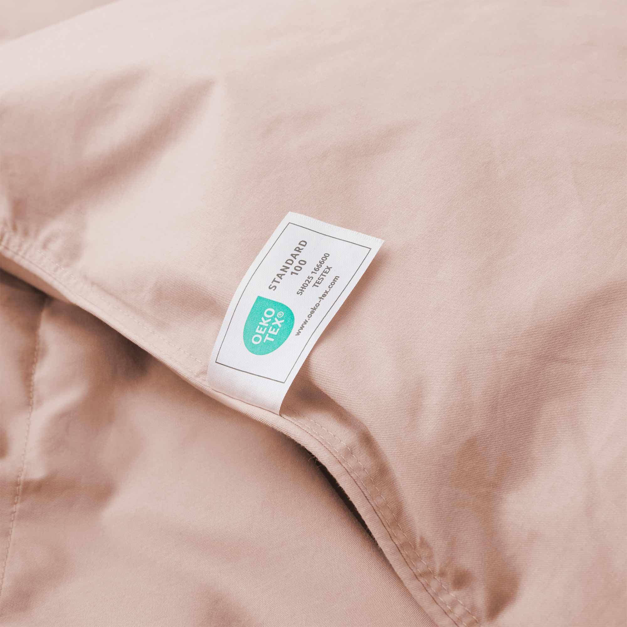 The Premium Goose Feather Comforter features beige fabric with an OEKO-TEX Standard 100 certification label attached to the surface.