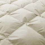 Close-up of the Premium Goose Feather Comforter in beige, featuring a soft, puffy texture and a quilted square stitching pattern.