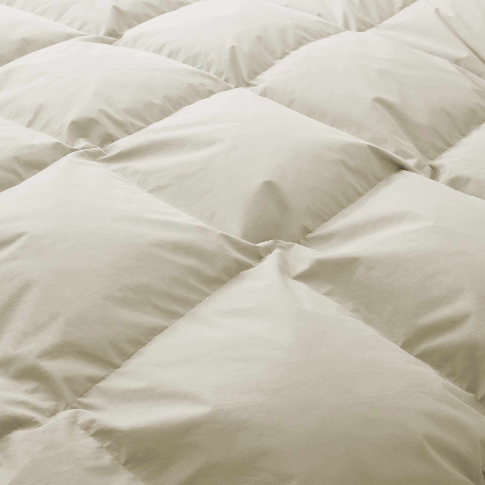 Close-up of the Premium Goose Feather Comforter in beige, featuring a soft, puffy texture and a quilted square stitching pattern.