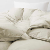 Close-up of the Premium Goose Feather Comforter in beige, featuring a fluffy texture on a bed with a white pillow in the background.