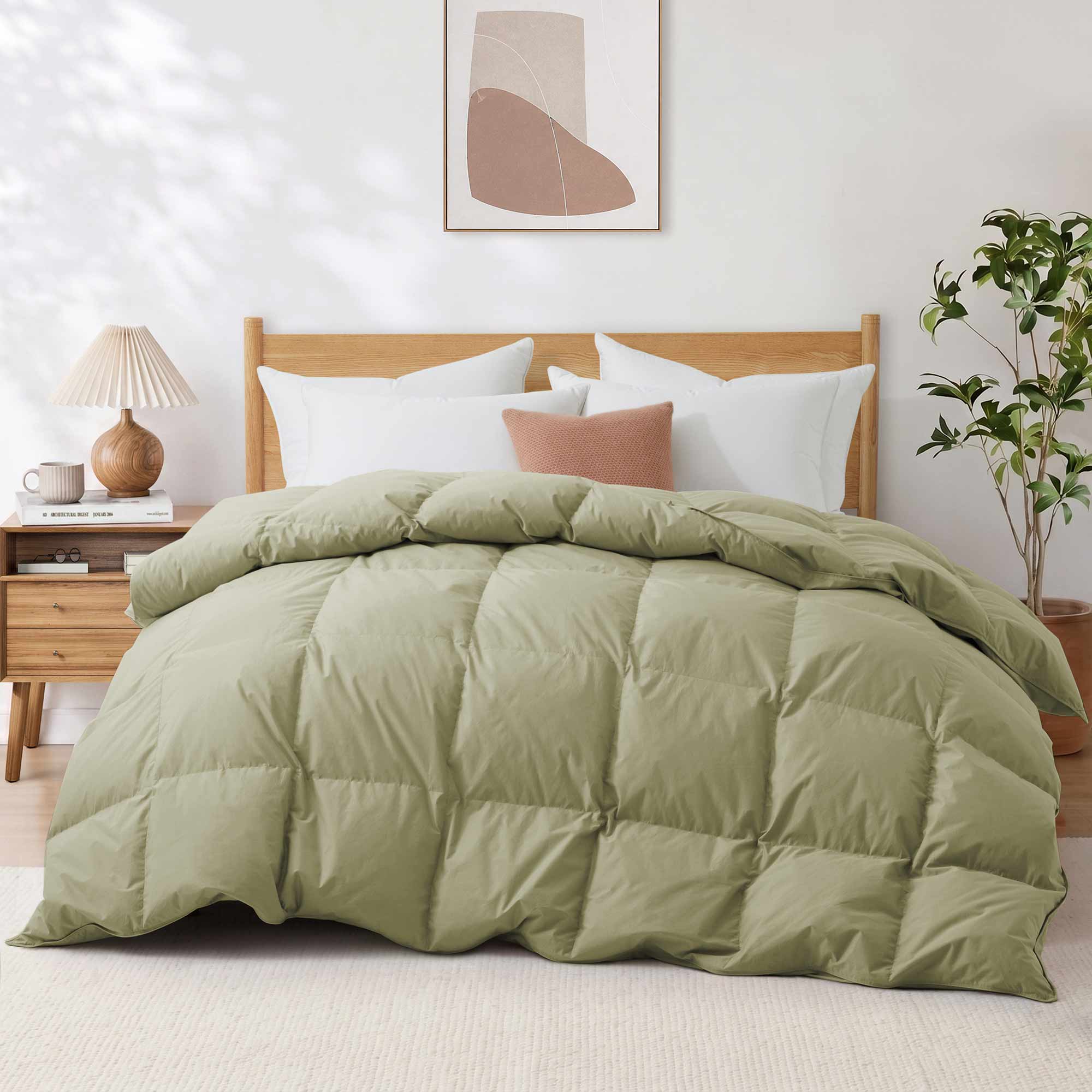 A neatly made bed featuring the Premium Goose Feather Comforter in green, complemented by white pillows, a nightstand, and modern wall art above.