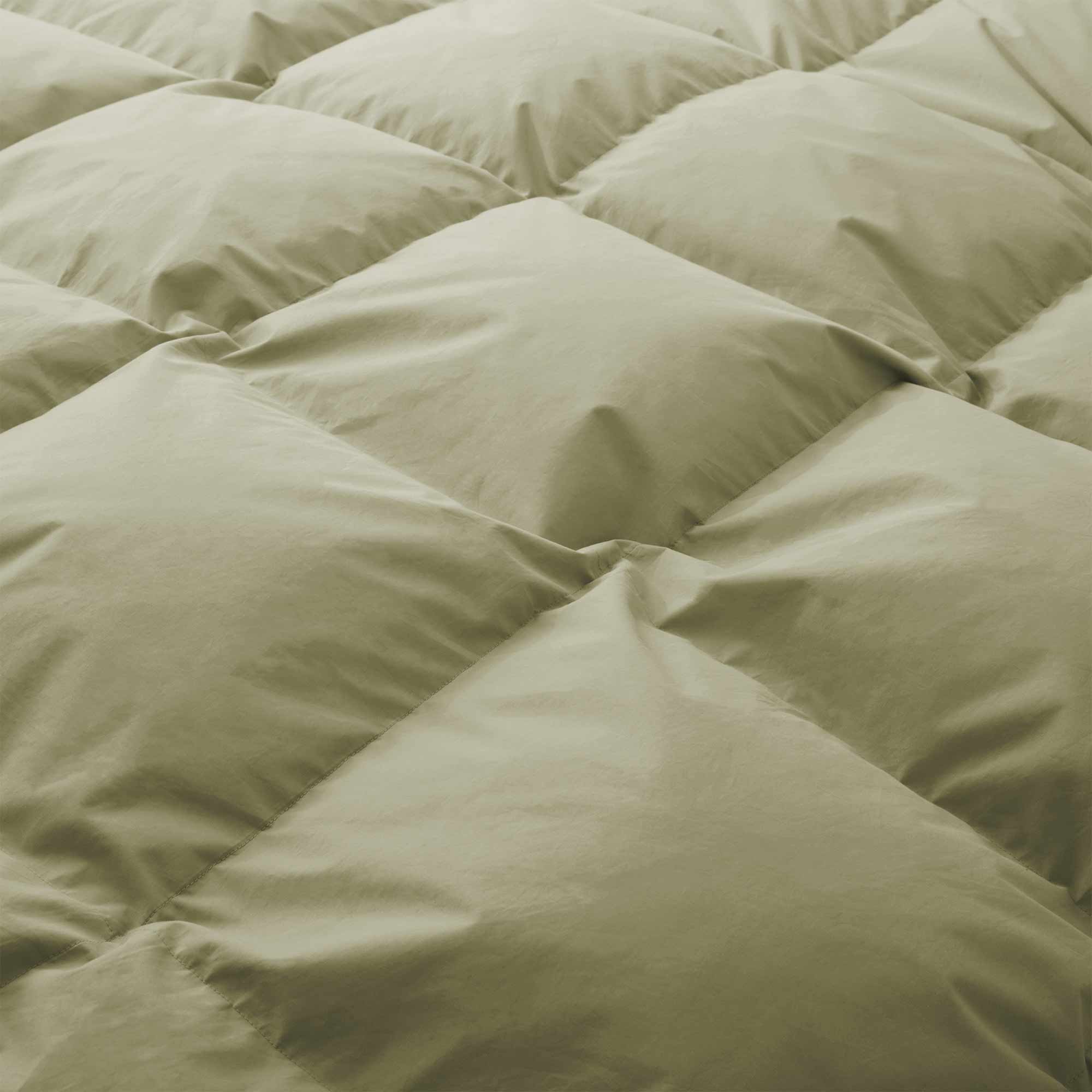 Close-up of the Premium Goose Feather Comforter in light green, featuring soft, puffy quilted square sections.