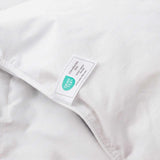 Close-up of the Premium Goose Feather Comforter in white fabric, featuring an Oeko-Tex certification label sewn onto it.