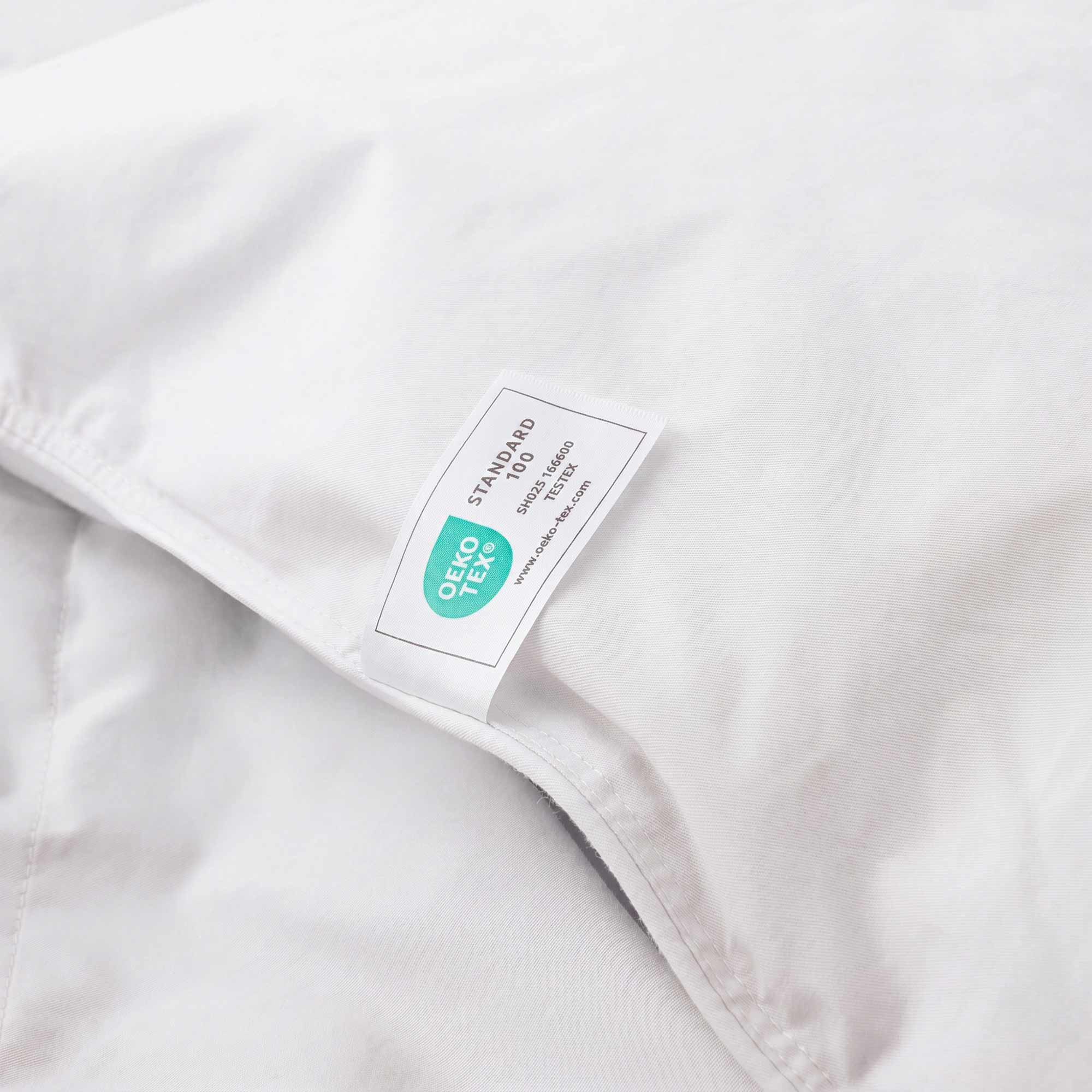 Close-up of the Premium Goose Feather Comforter in white fabric, featuring an Oeko-Tex certification label sewn onto it.