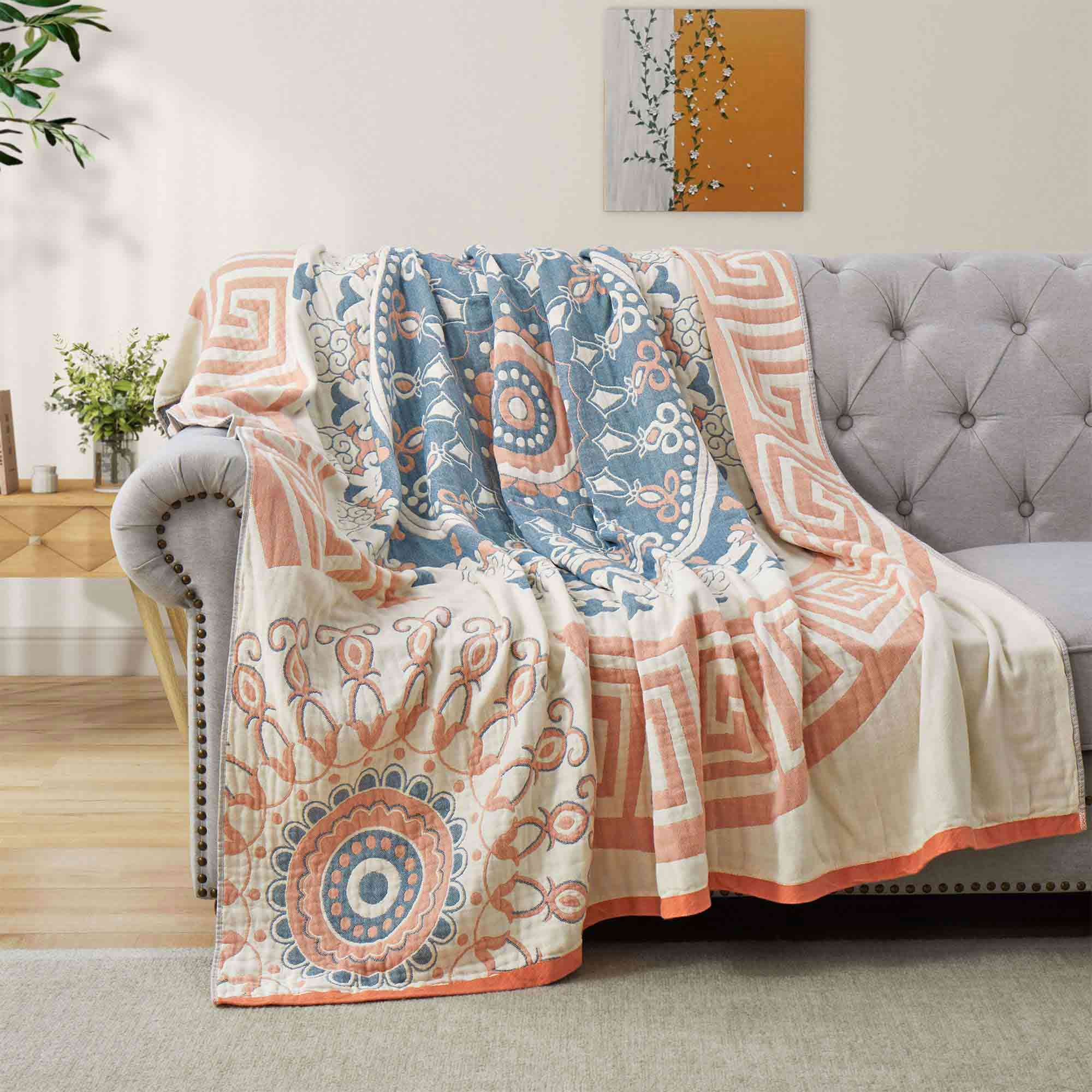 Cream-colored velvet throw blanket with intricate orange and navy medallion and vine patterns, finished with a navy blue border.
