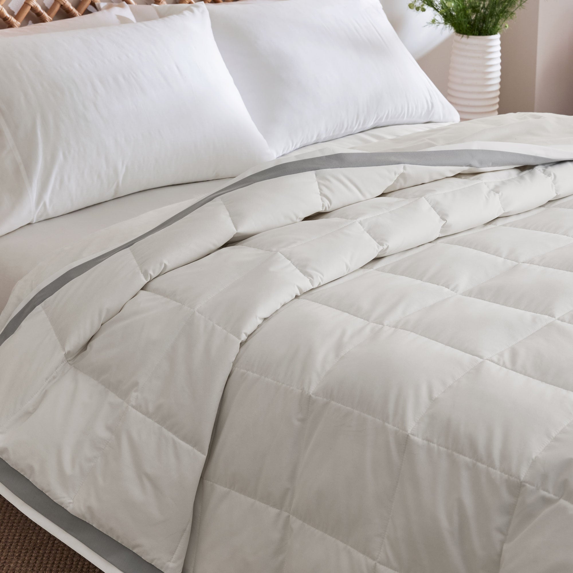 The twin down blanket is brushed in the soft tones of cloud white with a contrasting deep grey trim. Add a touch of elegance to your bedding with this cool blanket for summer in white.