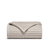 The all-weather blanket is covered in a beige color with soft camel undertones. Add a dimensional texture to your modern home décor with this perfectly pretty warm-season blanket for comfort.